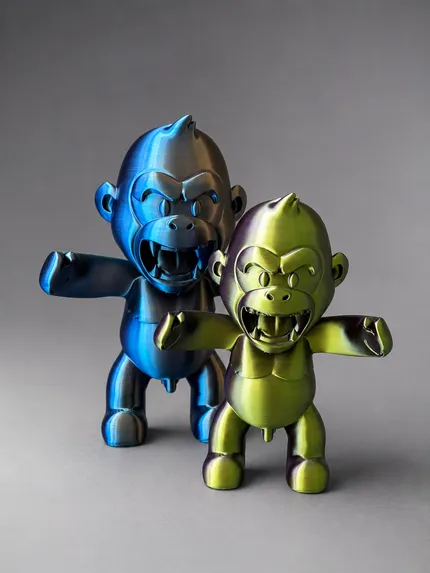 Twee 3D-geprinte brullende gorilla's naast elkaar, links in blauw-brons silk, rechts in goud-groen silk